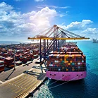 Een indrukwekkend luchtfoto van een groot roze containerschip vol geladen met kleurrijke vrachtcontainers, aangemeerd bij een havenkade met grote kranen